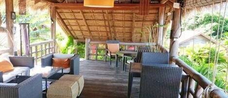 An outdoor seating area with wicker furniture and a thatched roof structure.