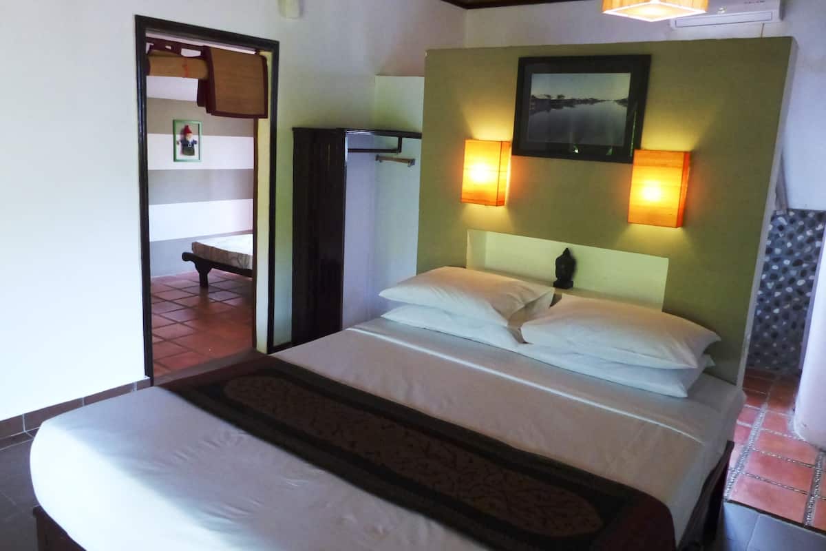 A hotel room with a bed, a nightstand, a wall-mounted TV, and a door leading to a balcony.