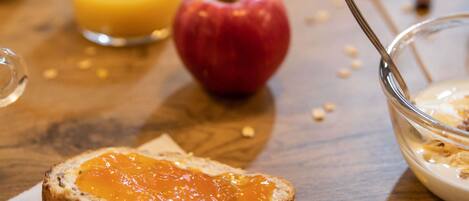 A breakfast setting with toast, apple, orange juice, and a bowl of cereal.