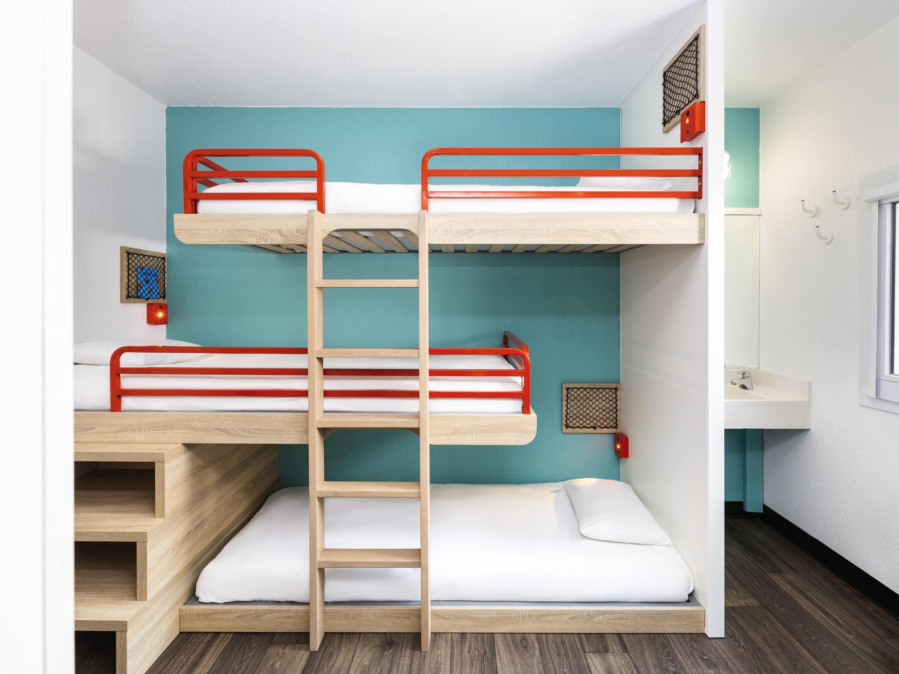 A bunk bed room with a wooden ladder, a white sink, and a window.