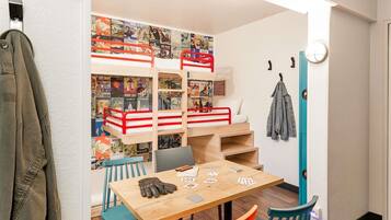 Ein Zimmer mit einem Etagenbett, einem Tisch mit Spielkarten und einer Wand, die mit Reisepostern dekoriert ist.