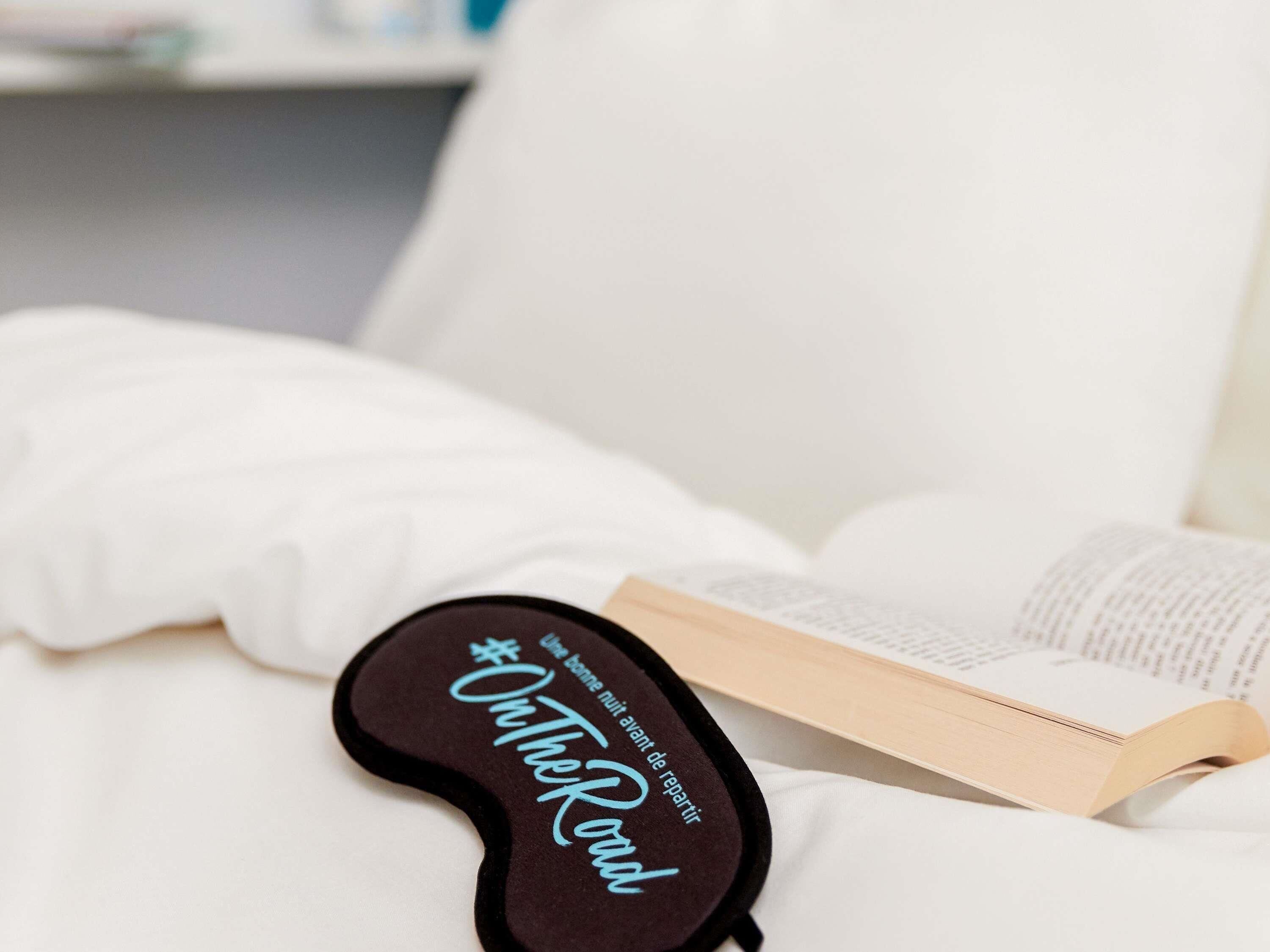 A book and a black object with text on a white bed.