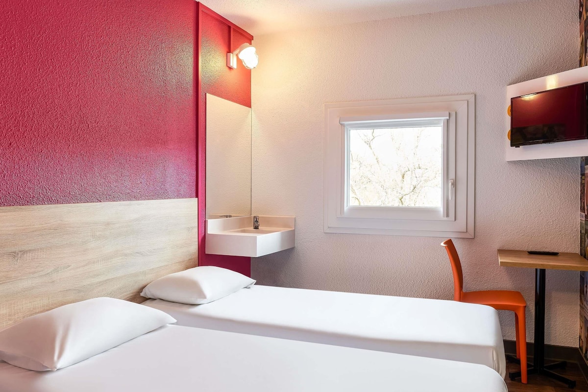 Una habitación de hotel con una cama, un ventanal, un escritorio y una silla.