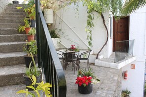 A courtyard with stone steps, potted plants, a table with chairs, and a wooden door. - Camping Tropical (Almunecar)