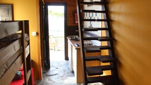 A narrow hallway with a wooden bench on the left, a kitchen area with a sink and stove, and a wooden ladder against the wall. - Camping Tropical (Almunecar)