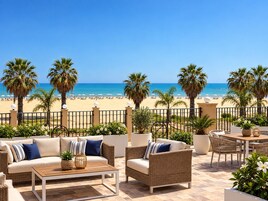 Una terrazza con mobili da esterno, vista sulla spiaggia e palme.