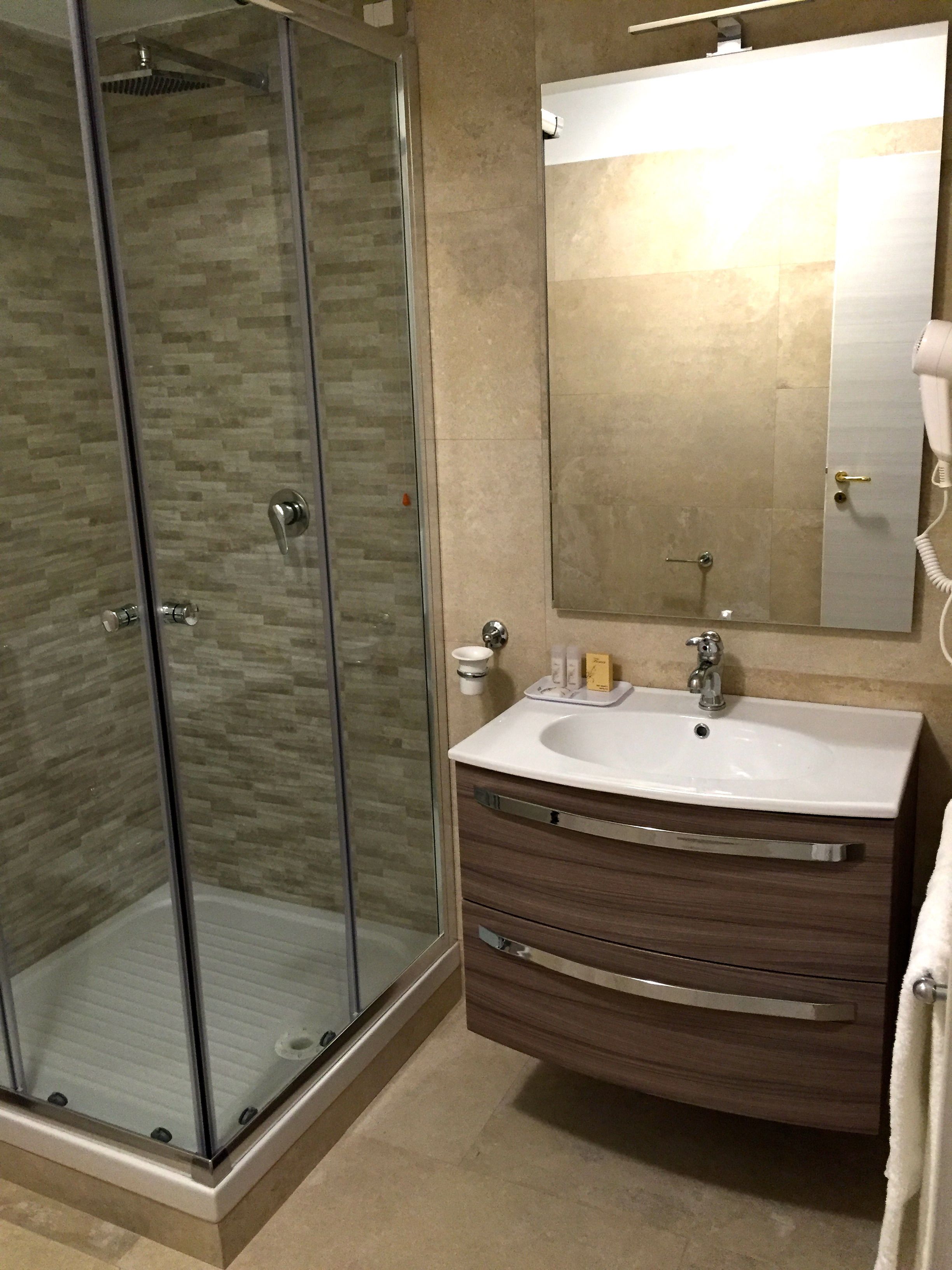 A modern bathroom with a glass shower enclosure, a vanity with a sink, and a mirror above it.