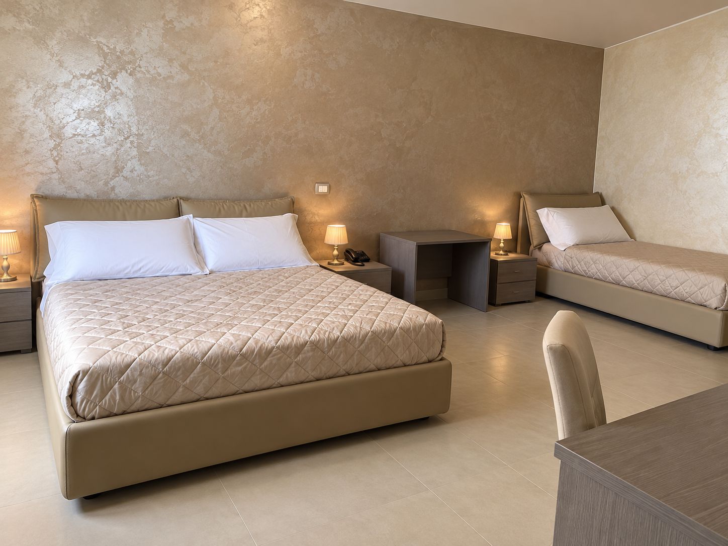 A hotel room with a large bed, two bedside tables, a desk, and a chair.