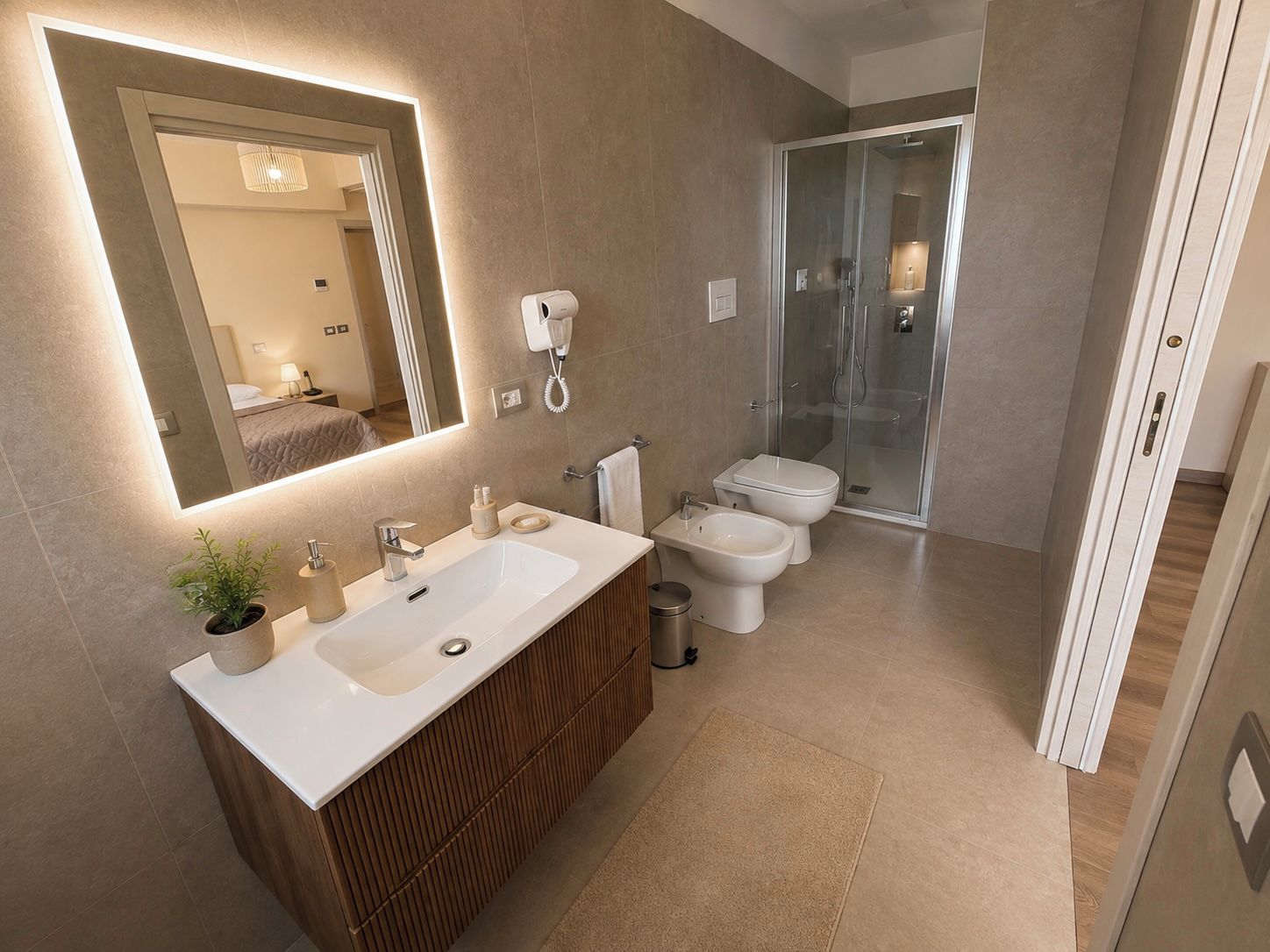 A modern bathroom with a large mirror, dual sinks, a toilet, and a glass shower enclosure.