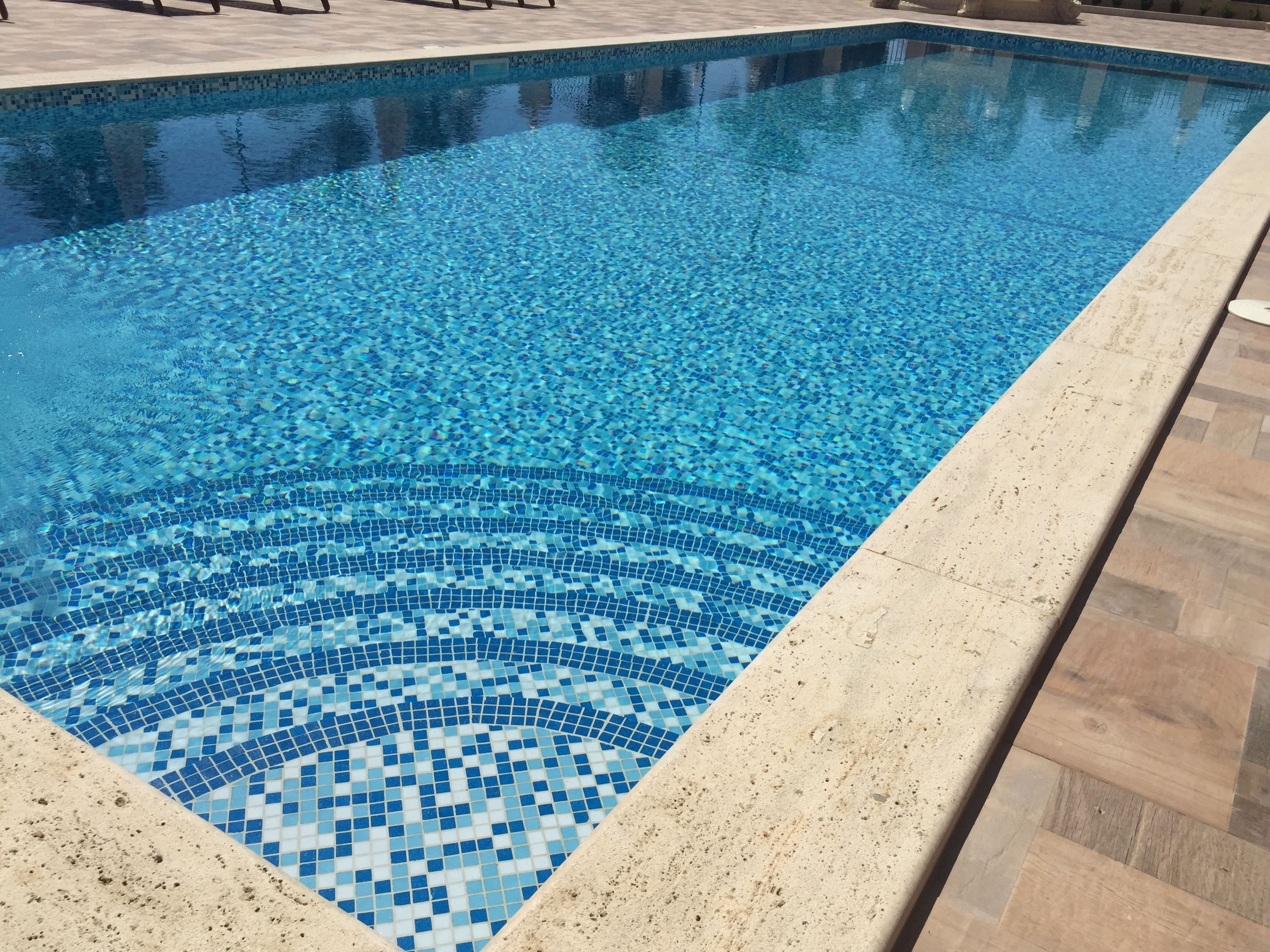 Una piscina rectangular con un diseño de mosaico en el fondo.