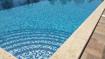 Una piscina rectangular con un diseño de mosaico en el fondo.