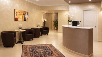 A reception area with a reception desk, seating, a patterned rug, and a chandelier.