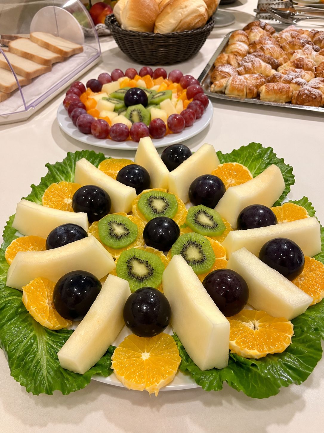 A buffet table with a variety of food items including fruits, cheese, and bread.