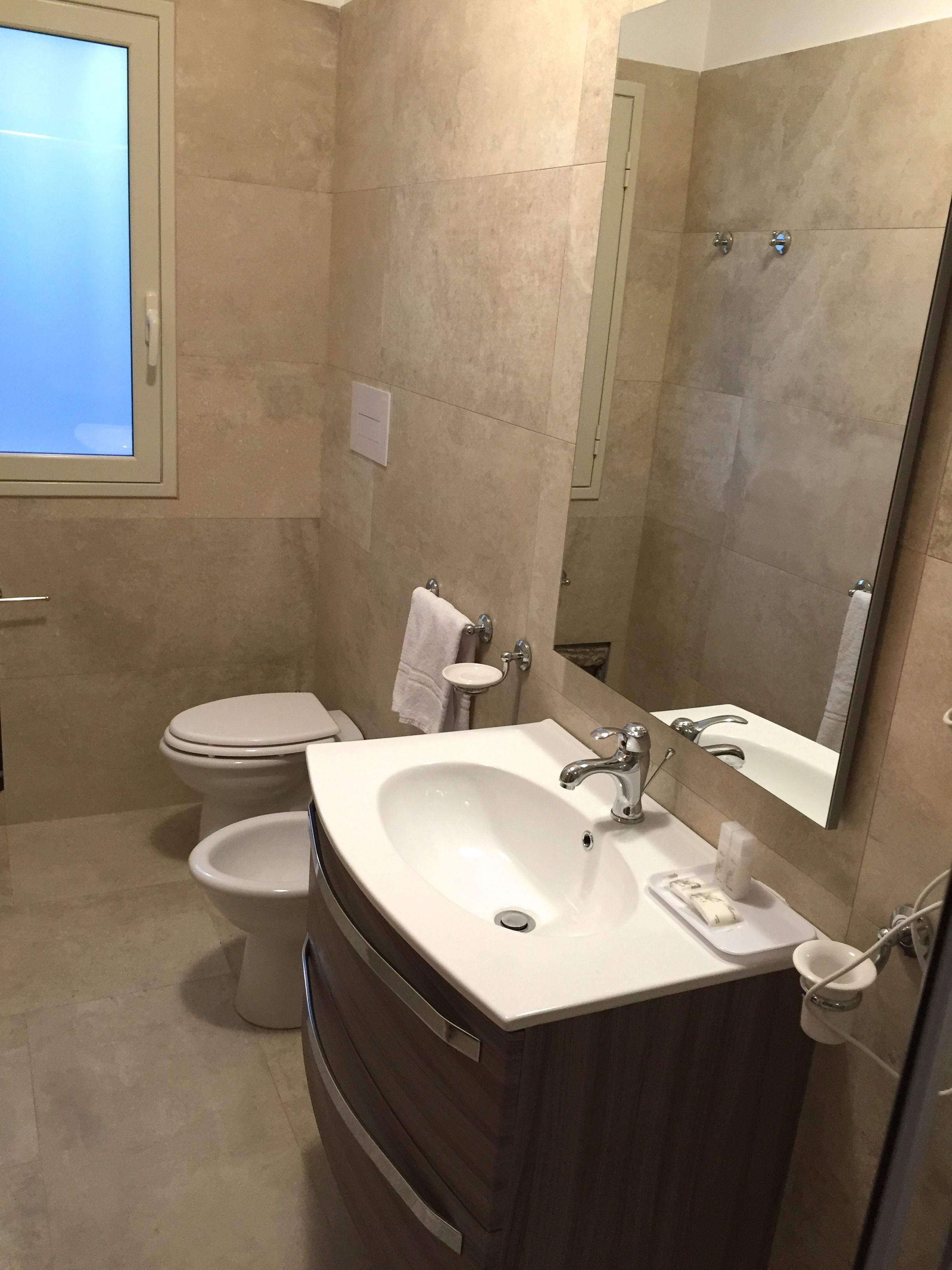 Un baño con lavamanos, espejo y retrete.
