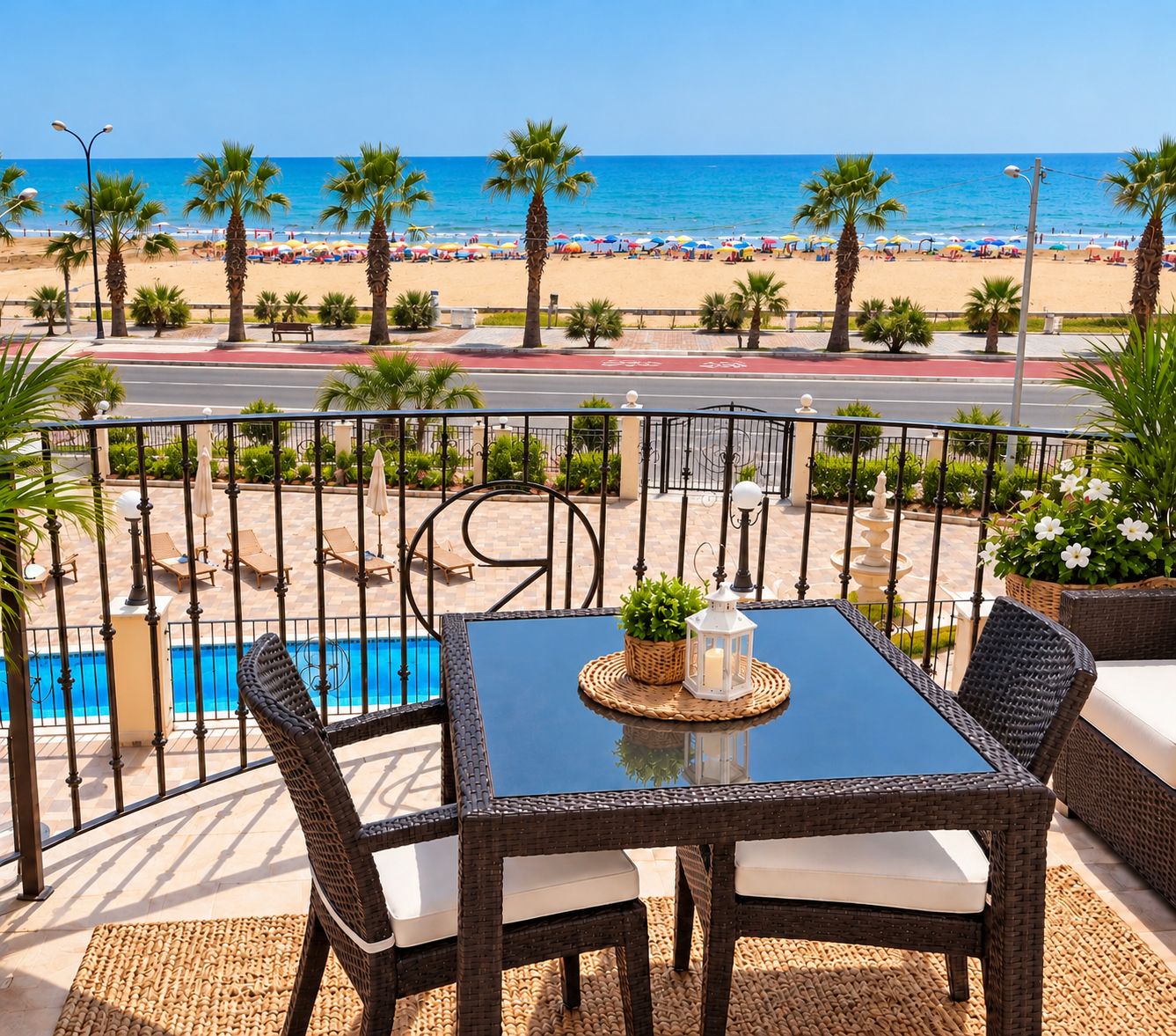 A balcony with wicker furniture, a pool, and a view of the beach.