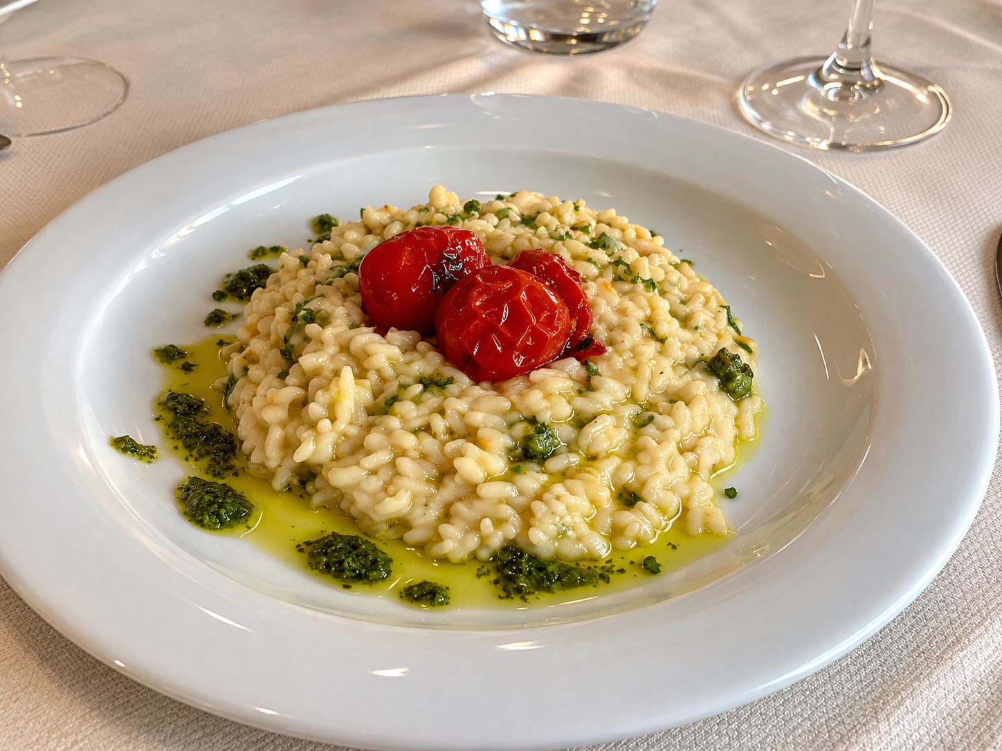 A plate of risotto with cherry tomatoes and pesto.