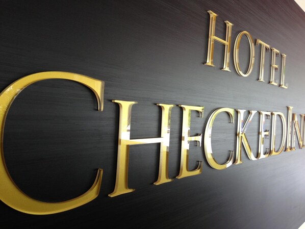 A sign with the words "HOTEL CHECKED IN" in gold lettering on a dark background. - Hotel CheckedInn (Ipoh)