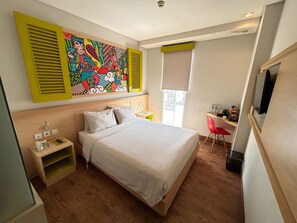 Ein Hotelzimmer mit einem Bett, einem Schreibtisch, einem Sessel, einem Gemälde und einem Fernseher.