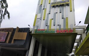 Ein Gebäude mit einem Schild, auf dem 'Grand Gado-Gado BOPLO' und 'Maxone Hotels.com' steht.
