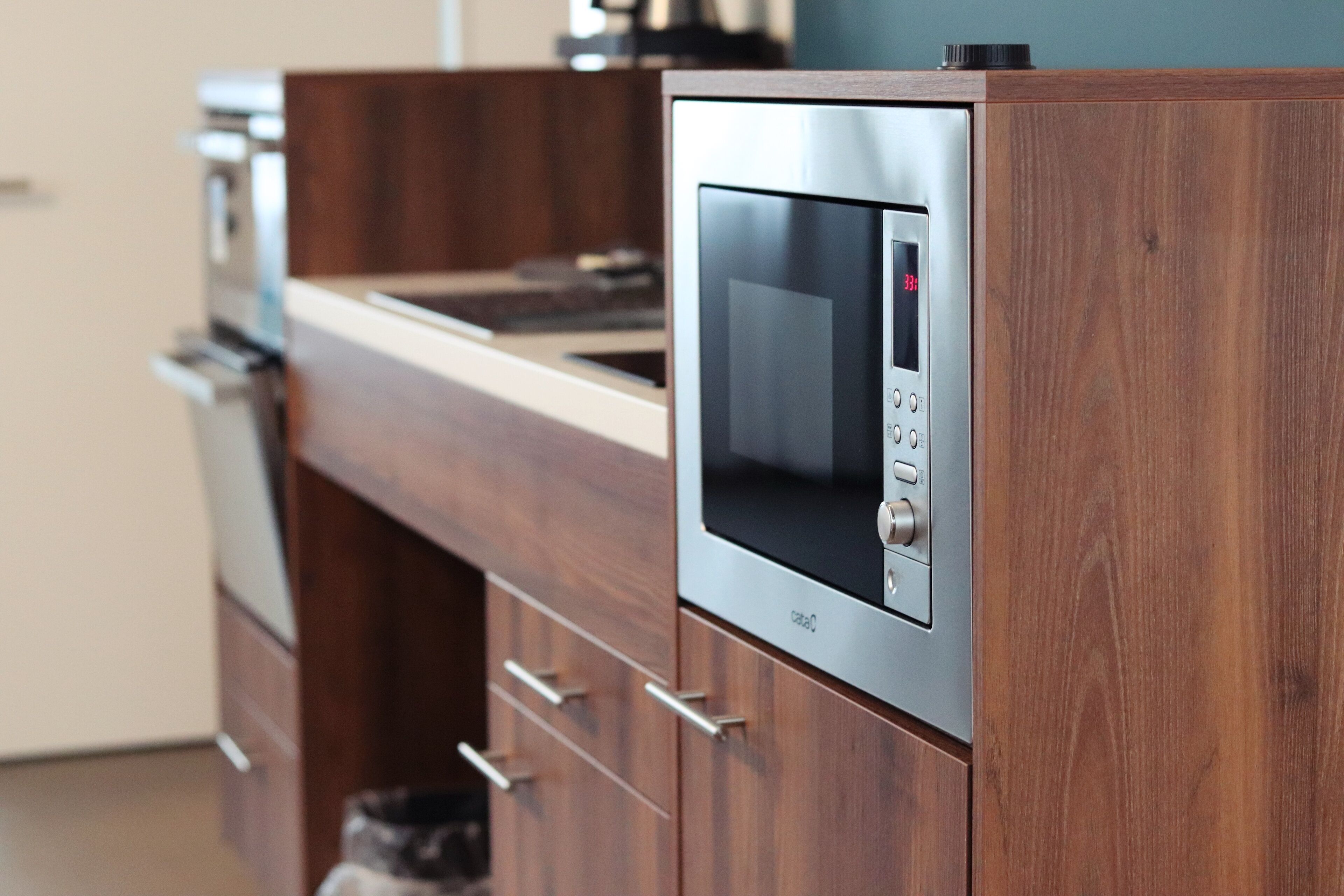 Una cocina con microondas integrado, armarios de madera y horno de acero inoxidable.