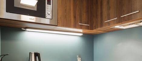 A modern kitchen with wooden cabinets, stainless steel appliances, and a white countertop.