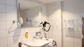 A modern bathroom with a sink, mirror, towel rack, and glass shelves.