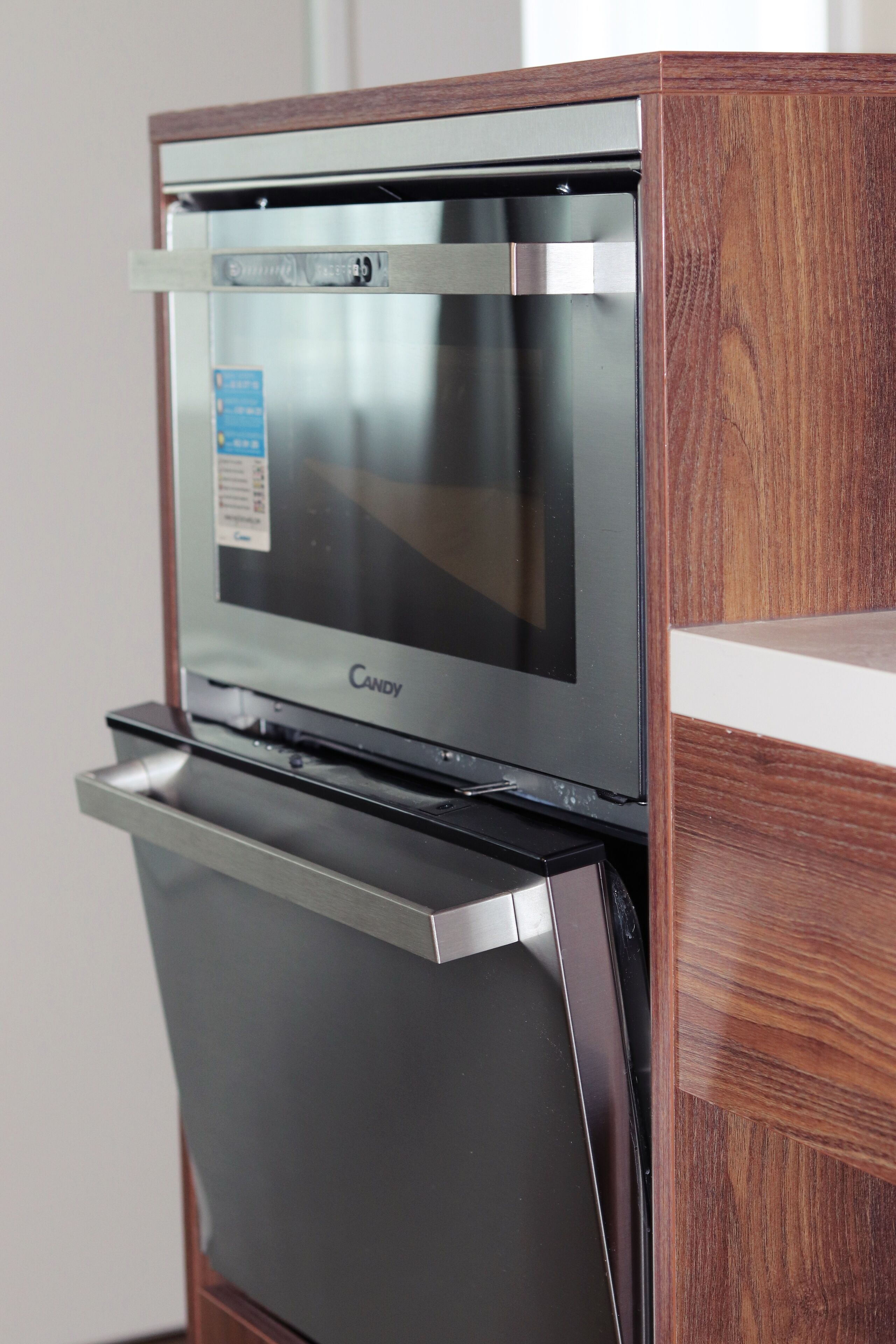Una cocina con microondas y horno integrados, y un armario de madera sobre el horno.