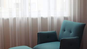 Une chaise placée devant une fenêtre ornée de rideaux légers.