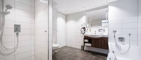 A modern bathroom with a walk-in shower, a toilet, a sink with a mirror, and a bathtub.