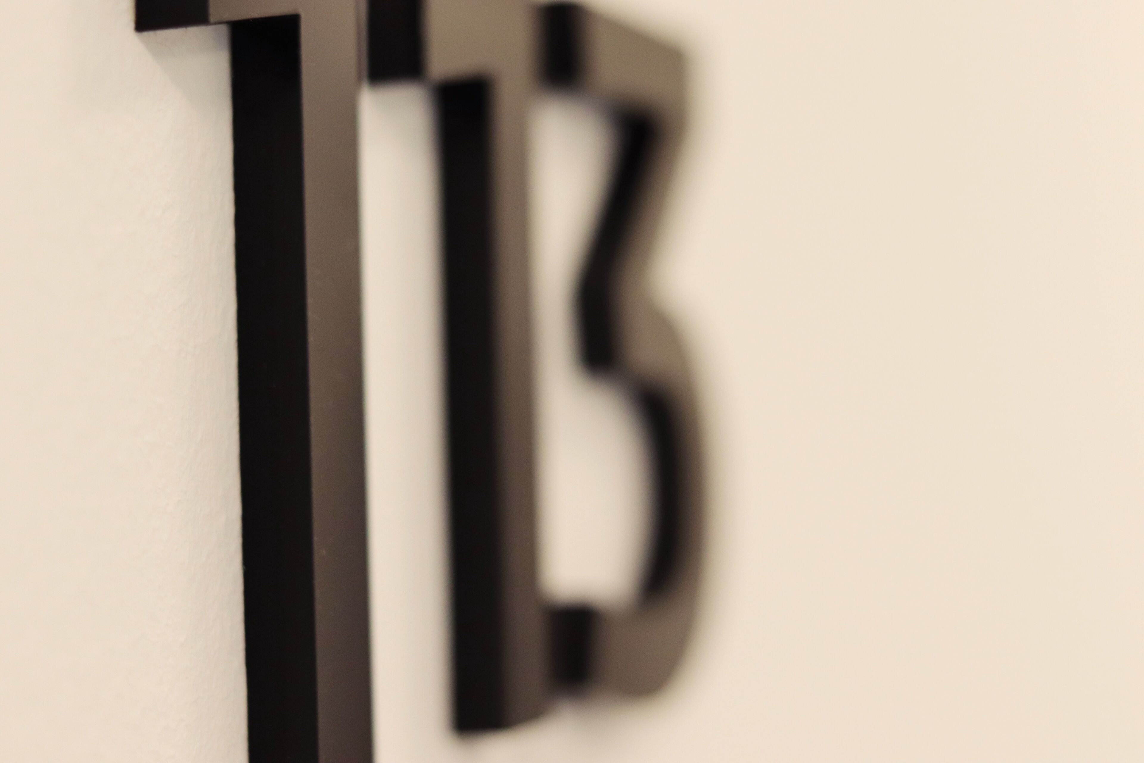 Primer plano de una letra 'B' negra sobre una pared blanca.