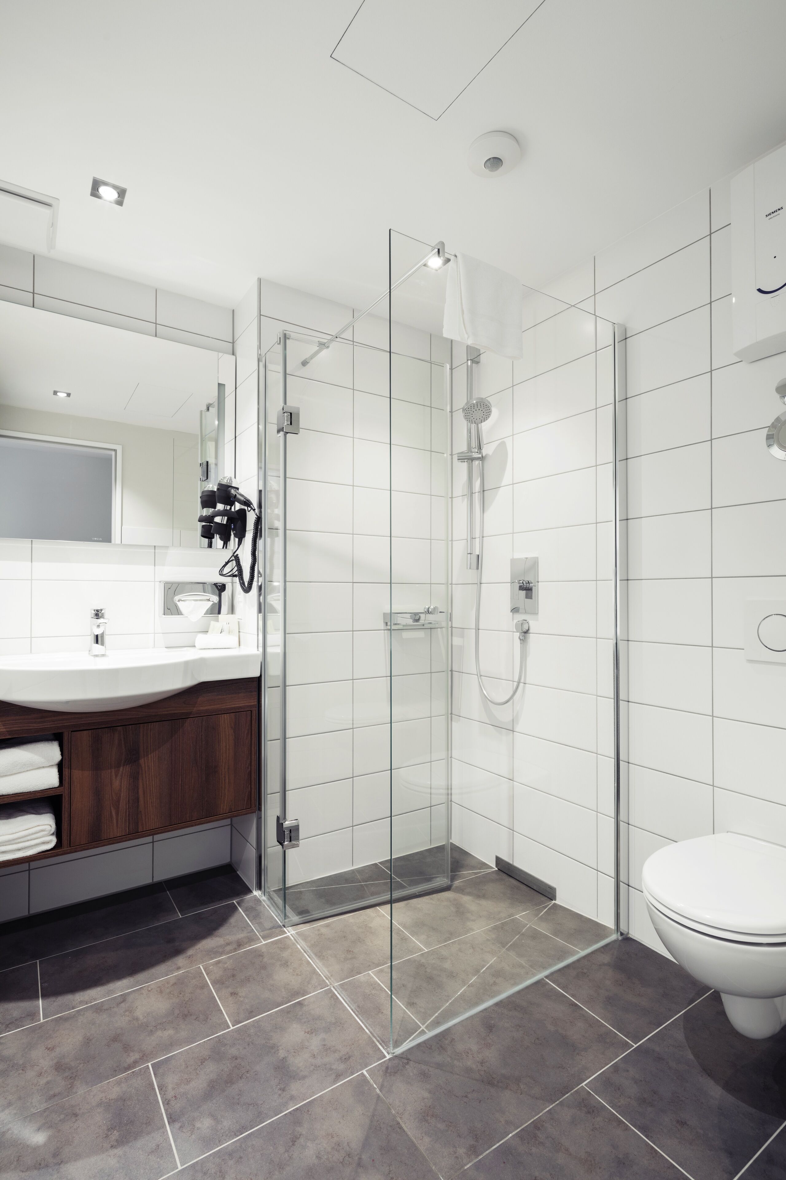 A modern bathroom with a glass-enclosed shower, a white sink, and a toilet.