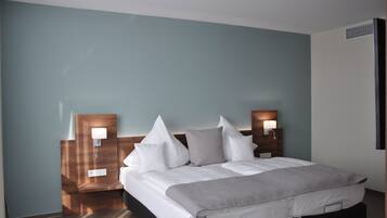 Una habitación de hotel con cama, dos mesitas de noche con lámparas y un aplique de pared.