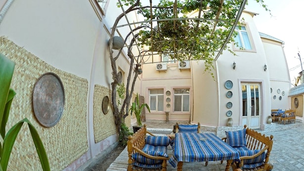 Un patio tradicional con una mesa y sillas de madera, un muro tejido y una planta en maceta.