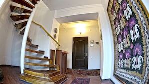Una escalera de madera con barandilla que conduce a una puerta de madera oscura.