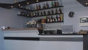 Una zona de bar con estantes llenos de botellas, una máquina de café y un reloj en la pared.