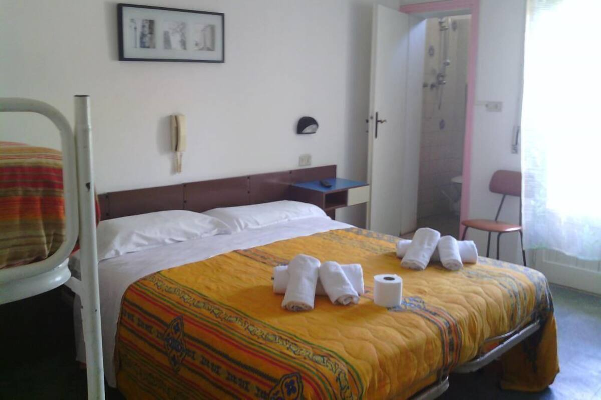 A hotel room with a bed, a chair, a desk, and a shower area.