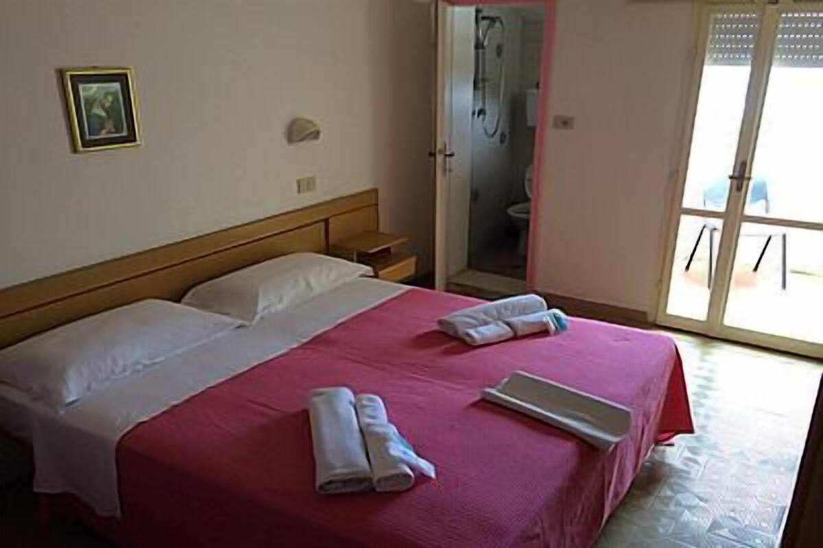 A hotel room with a bed, a shower, and a view of the outside.