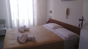 Una habitación de hotel con una cama, una silla, un teléfono y una ventana con cortinas.