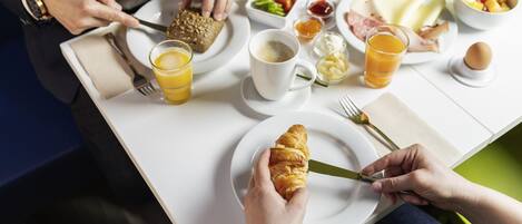 A breakfast table with croissants, eggs, and juice.