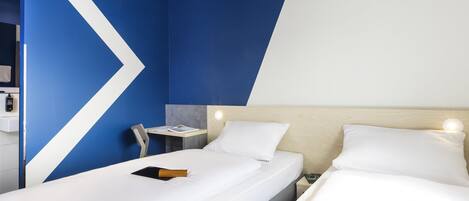 A hotel room with two beds, a desk, and a chair.