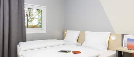 Una habitación de hotel con una cama, una mesita de noche, una ventana y vistas a árboles.