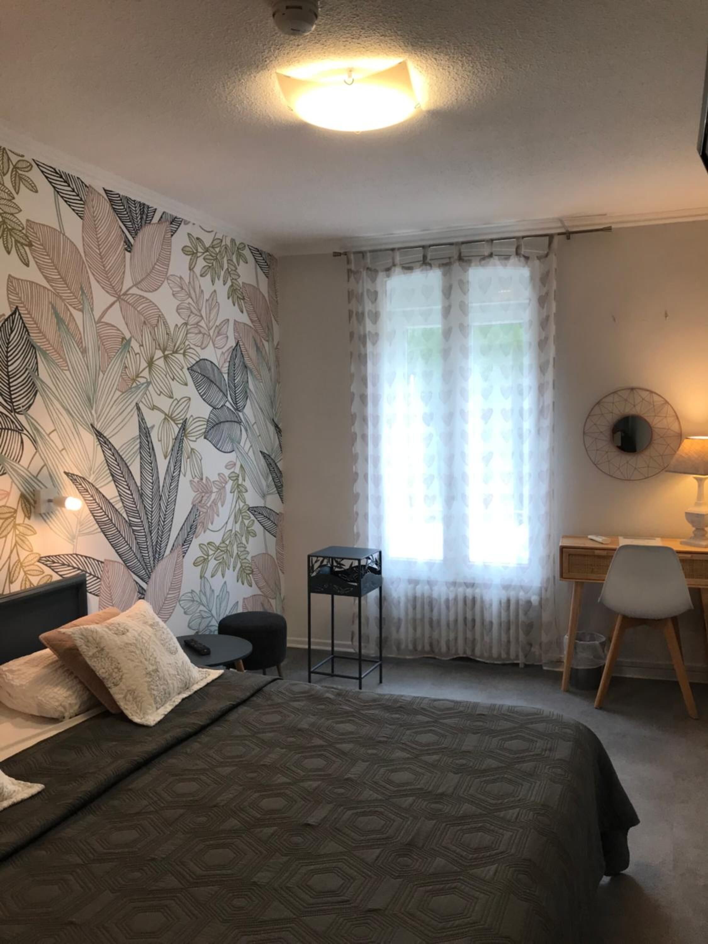 A bedroom with a bed, a desk, a chair, and a small table.
