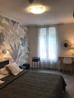 Un dormitorio con cama, escritorio, silla y una mesita.