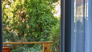 Eine Terrasse im Freien mit einem blauen Metalltisch und -stühlen, umgeben von Holzzaun und Grünpflanzen.