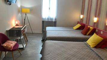 A hotel room with two beds, a desk with a chair, a television, and a window with curtains.