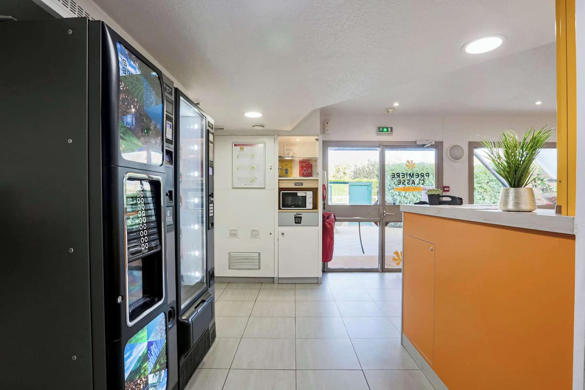 A hotel lobby with a vending machine, a microwave, a small kitchenette, and a reception desk.