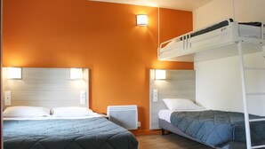 A hotel room with two beds, a bunk bed, and a wall-mounted heater.