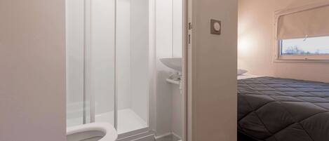 Un baño con cabina de ducha de vidrio, inodoro y lavabo.