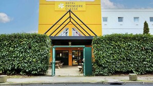 A hotel entrance with a yellow facade and a sign reading "HOTEL PREMIERE CLASSE".