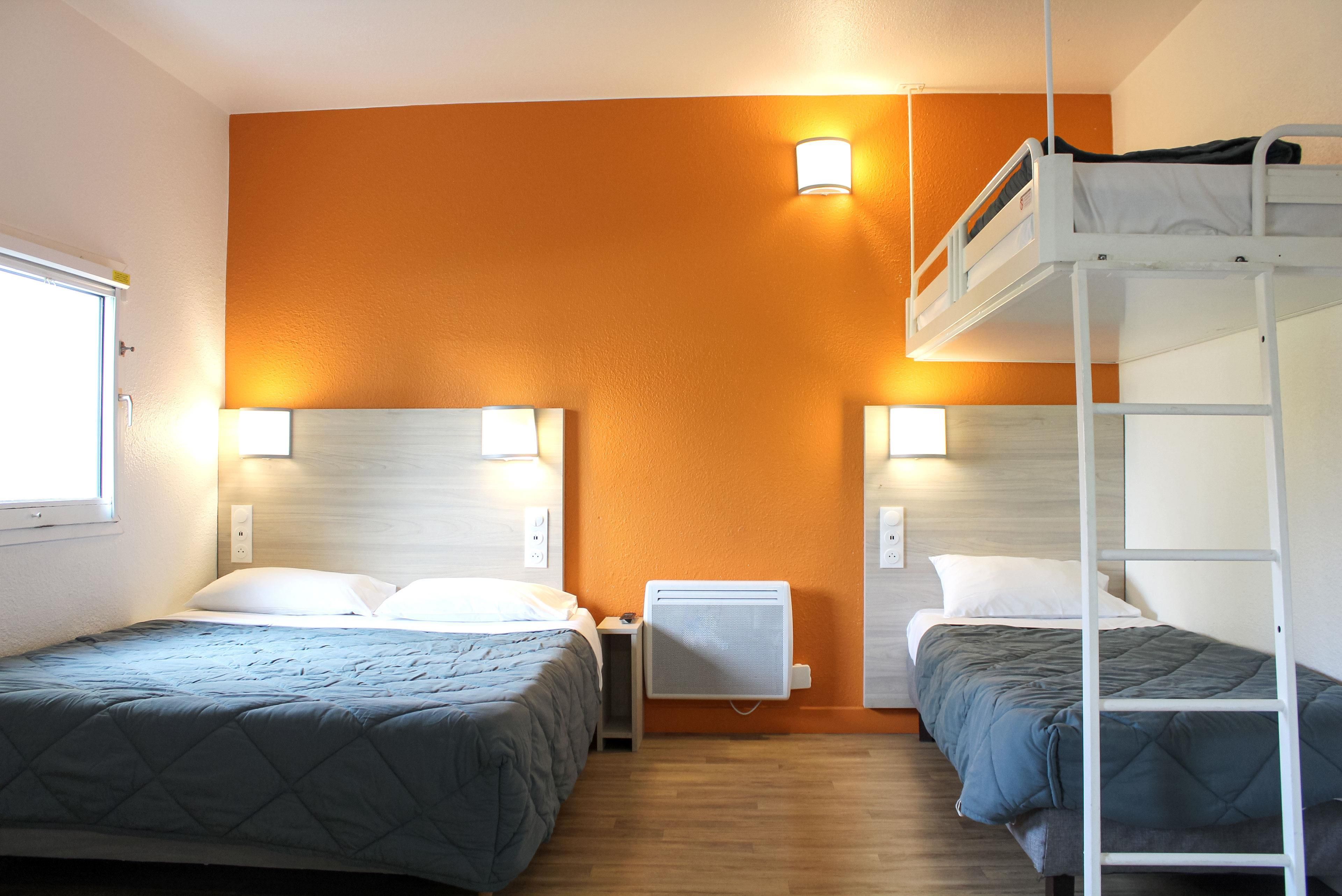 A room with two beds, a bunk bed, a heater, and a window.